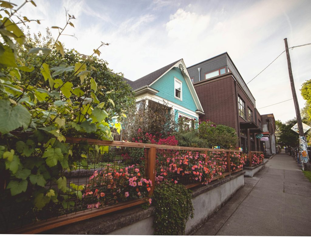 Grün-weißes Holzhaus in der Nähe grüner Bäume unter weißen Wolken am Tag